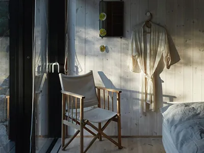 A minimalist bedroom with wooden walls and a wooden folding chair.