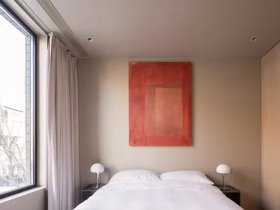A minimalist bedroom with a large bed, two nightstands, and a large painting on the wall.