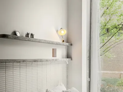 A minimalist bedroom with concrete headboard and grey bedding, featuring a floating concrete shelf with a table lamp and smal