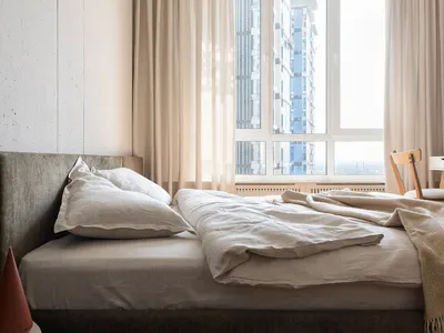 A minimalist bedroom with concrete walls and linen furnishings, showcasing a serene and modern design.