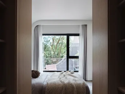 View of a minimalist bedroom with wooden furniture and fabrics.