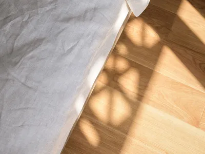 A neatly made bed with minimalist bedding on a wooden floor.