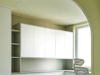 A minimalist home office featuring white cabinets.