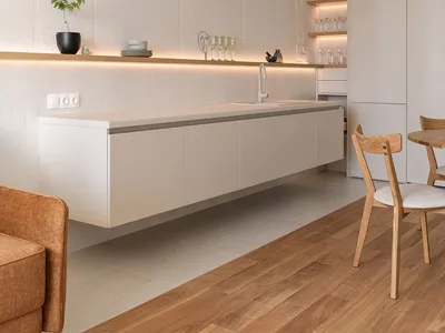 A modern minimalist kitchen with a concrete backsplash, floating cabinets, and a floating countertop featuring a sink and fau