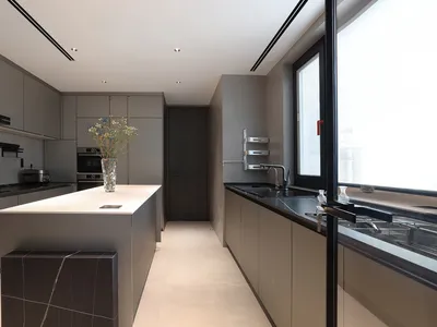 Modern minimalist kitchen with white countertops, concrete flooring, and glass window.