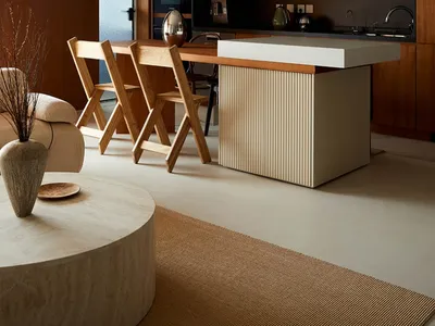 Modern minimalist kitchen with a concrete countertop and wooden seating area.