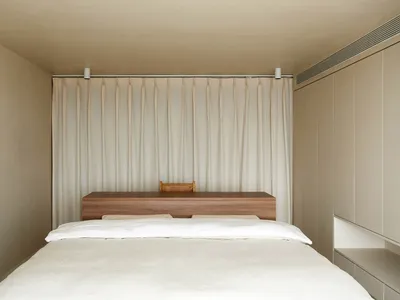 A minimalist bedroom featuring a wooden headboard and curtain.