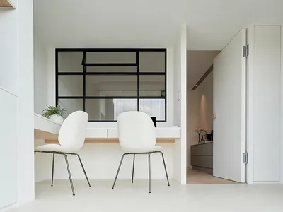 A minimalist home office featuring a sleek, white minimalist desk and chairs with black frames, set against a white backgroun