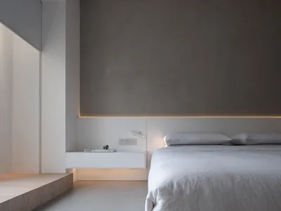 極簡臥室，配有混凝土床頭板與白色寢具，簡約設計。