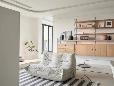 Modern minimalist living room featuring wood furniture and a striped rug.
