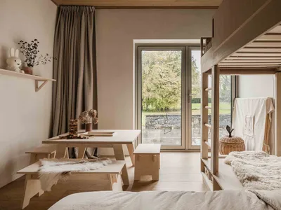 Minimalist bedroom with wooden furniture and a window overlooking a garden.