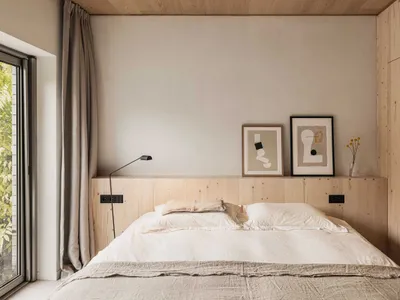 A modern minimalist bedroom with a wooden headboard and abstract art.