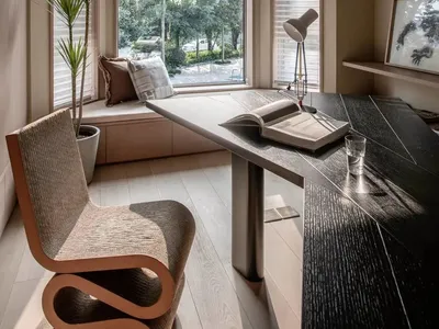 A modern minimalist home office space featuring a sleek wooden desk, glass windows, and a comfortable seating area with natur