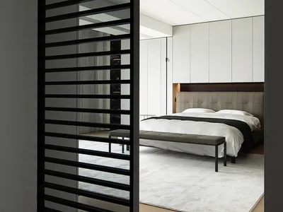 Modern minimalist bedroom with a white bed, grey headboard, and metal frame furniture.