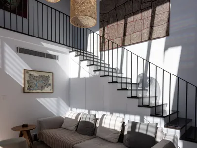 A modern living room with a comfortable couch, artistic wall decor, and large bamboo pendant lights hanging from a vaulted ce