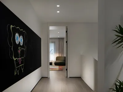 A modern home office with white walls and a blackboard on one wall, featuring a comfortable seating area and natural lighting