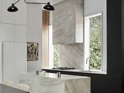 A modern kitchen with a marble countertop and wooden flooring.