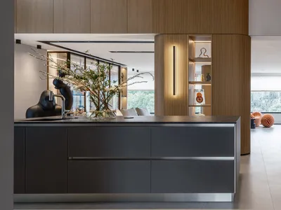 A modern kitchen with a wooden interior, featuring a dark countertop, white appliances, and minimalistic decor.