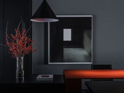 A minimalist restaurant interior features a sleek, modern concrete countertop and contemporary black walls.