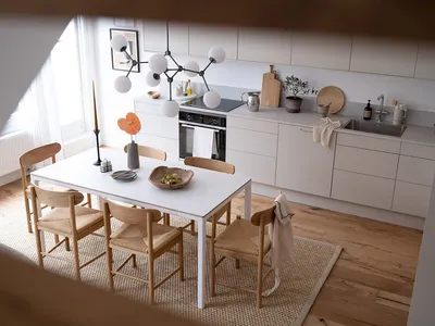 Modern minimalist kitchen with white cabinets, wood counter, and minimalist table setting.