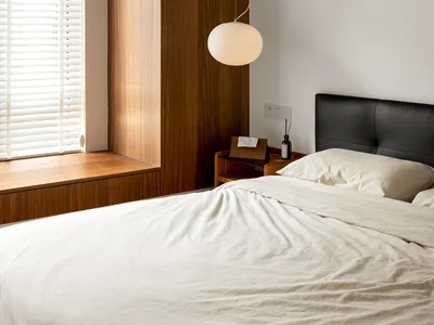 A minimalist bedroom with wooden walls, a bed, and a spherical hanging light fixture.