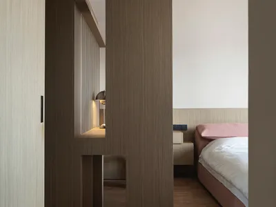 A minimalist bedroom featuring wooden furniture and floors.