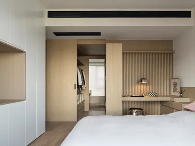 Modern minimalist bedroom featuring wood elements and a white bed with a pink pillow.
