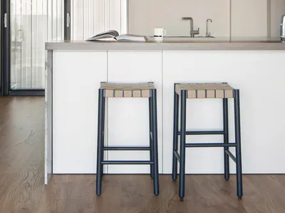 A modern kitchen with a wooden ceiling and floor, featuring a kitchen island with bar stools and a sink.