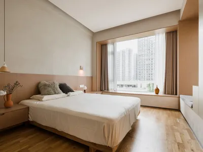 A modern minimalist bedroom featuring wooden furnishings and a large window overlooking a cityscape.