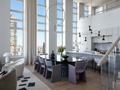 Modern living and dining area with glass table, wooden chairs, marble countertop, and large windows