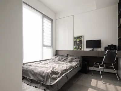 A modern bedroom with grey bedding and a minimalist design.