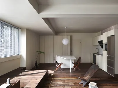 Modern kitchen with minimalist design elements, featuring a white countertop and wooden chairs.