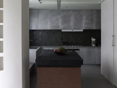 Modern minimalist kitchen with concrete countertops and dark metal cabinets.