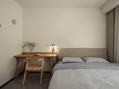Modern minimalist bedroom with a wooden bed frame and table, featuring grey bedding and a vase with greenery.