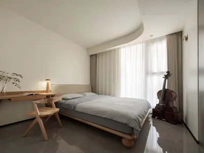 A minimalist bedroom with a wooden bed and table, featuring a Violin and white curtains on the window.