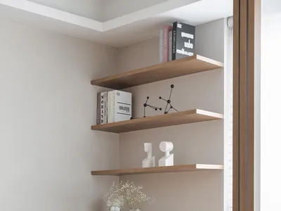 A modern home office space with a wooden desk and chair, featuring built-in shelves and a round rug.
