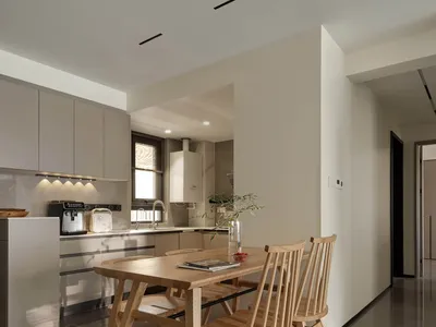 Modern kitchen with wooden table, marble countertops, and stainless steel appliances.