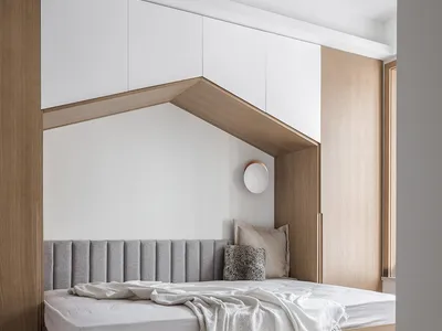 Modern minimalist bedroom featuring wooden furniture, white bedding, and a recessed sleeping area with a headboard and side t
