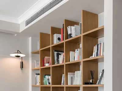 Modern industrial living room with a green plush sofa, wooden shelves filled with books, and a unique side table with a cylin