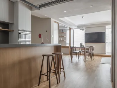 A modern kitchen featuring wooden cabinets and stools, metal accents, and a minimalist design.