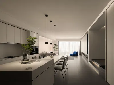 A modern minimalist kitchen with concrete and white countertops, pendant lights, and a green plant in a vase on the counterto