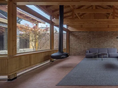 A spacious living room featuring dark wood flooring, a brick wall, and contemporary furniture.