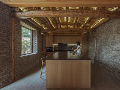 A minimalist residential kitchen with a wooden island and brick walls.