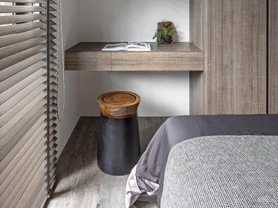 A minimalist bedroom with a floating desk, shelves, and a closed closet.
