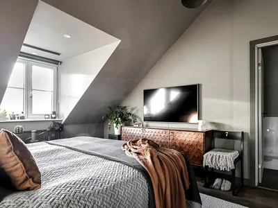 Modern minimalist bedroom with wood, metal, and natural-fiber materials, featuring a bed, TV, and window.