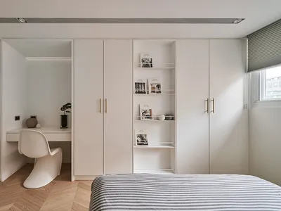 A minimalist bedroom featuring modern furniture with a bed and large closet.