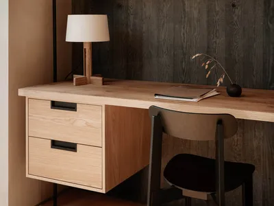 A minimalist home office featuring wooden furniture and a bookshelf with books and decorative items.
