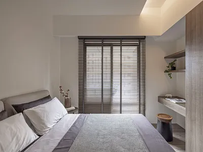 Minimalist bedroom with a wooden bed frame and window blinds.