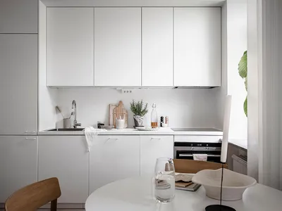 A minimalist white kitchen with modern cabinets and a clean, uncluttered design.