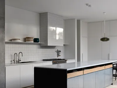 Modern minimalist kitchen with concrete flooring, stainless steel appliances, and white marble countertops.